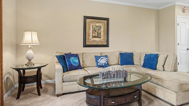A living room with a beige sofa, a glass coffee table, a lamp, and a framed picture on the wall. - Walk to the Beach, Shopping, and Dining. (Waikoloa Village)