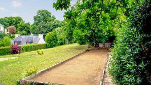 A courtyard with a paved area, surrounded by greenery and a building with a sloped roof. - 4 bedroom nice home in Binic (Binic)