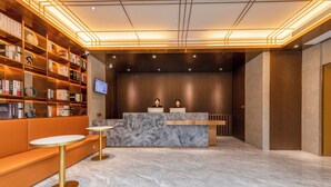 Un'accoglienza moderna con una reception in marmo, posti a sedere e una libreria piena di libri.
