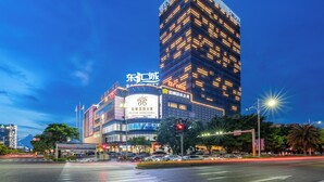 Un hotel a più piani con un cartello ben visibile per 'POLITTON INTERNATIONAL SERVICE APARTMENT' e un grande edificio illuminato sullo sfondo.