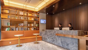 A modern reception area with a marble counter, seating, and a bookshelf with various items.