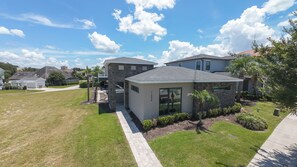 A residential property with a stone facade, a well-maintained lawn, and a clear sky. - Reunion Haven Villa-1209 (Kissimmee)