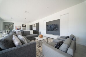 Ein modernes Wohnzimmer mit grauen Sofas, einem Couchtisch und einem großen abstrakten Gemälde an der Wand.