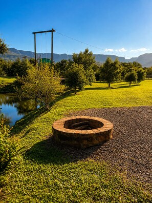 Un hogar circular en un área verde con árboles y un cuerpo de agua al fondo.