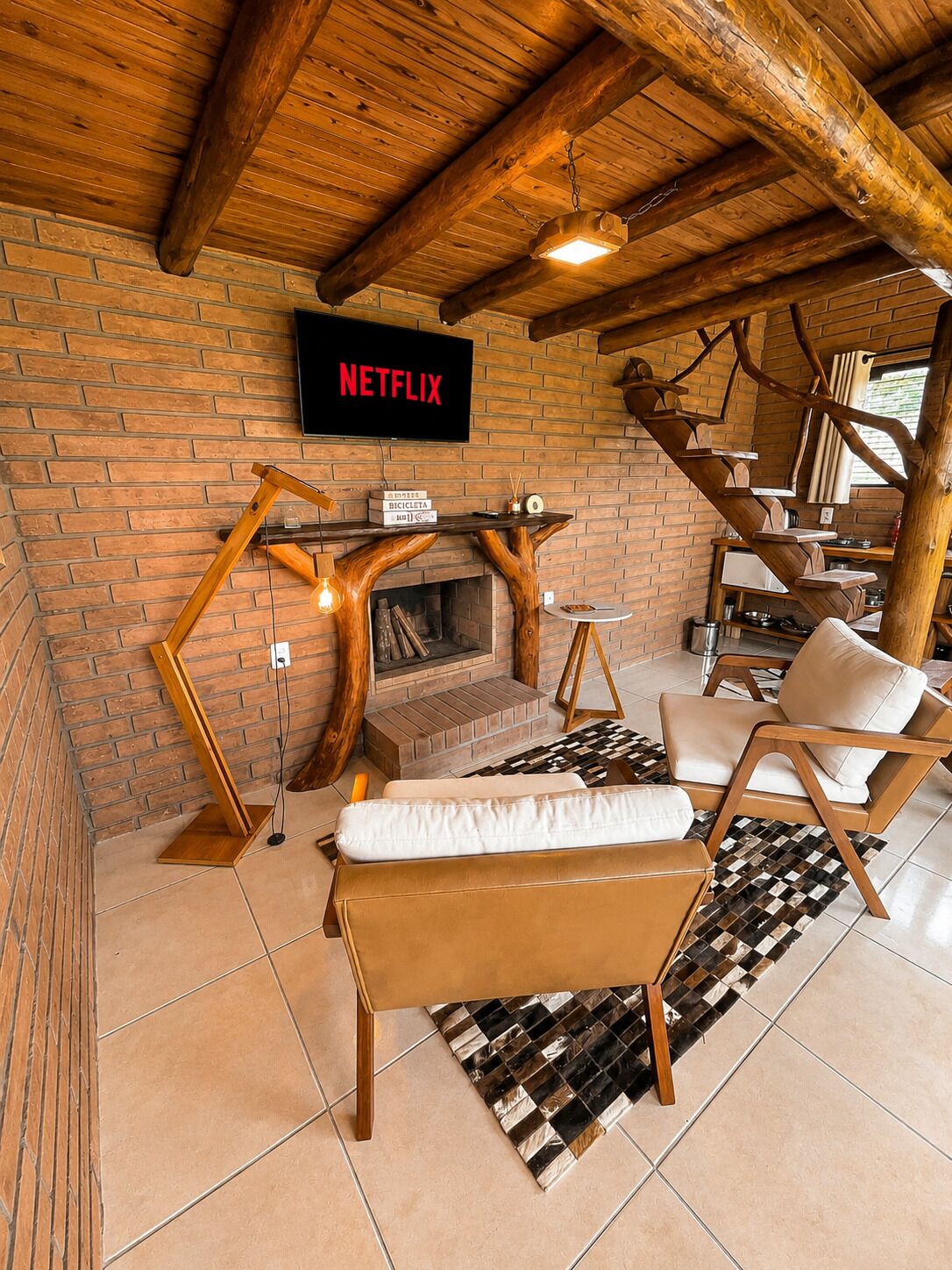 A cozy living area with a fireplace, a Netflix sign, and a wooden staircase.
