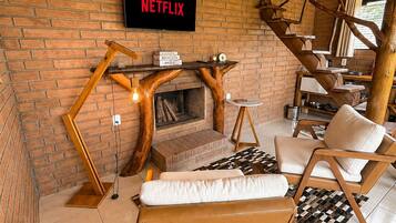 A cozy living area with a fireplace, a Netflix sign, and a wooden staircase.