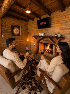 Una habitación acogedora con chimenea, televisor montado en la pared y suelo a cuadros.