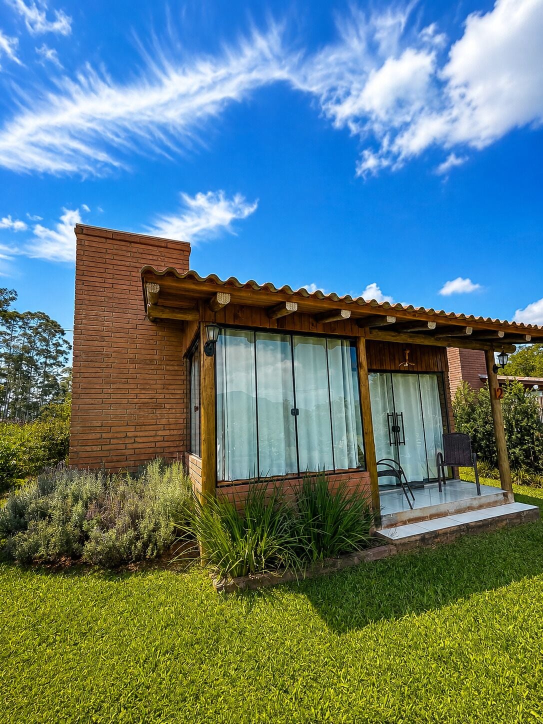 Una casa moderna con fachada de ladrillo, ventanas amplias y un patio cubierto.