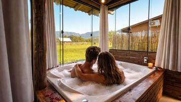 Una pareja en un jacuzzi con vistas a un campo verde y montañas.