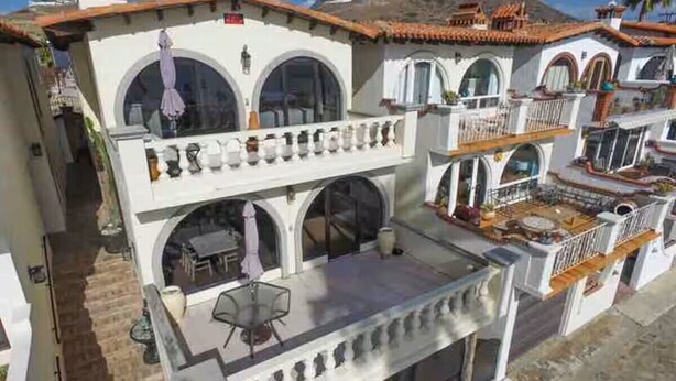 A multi-story building with balconies, arched windows, and outdoor seating areas.