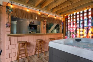 A tiki bar with wooden stools, a bar counter, and a hot tub. - Spacious Corolla retreat w/ hot tub and rec room! (Corolla)