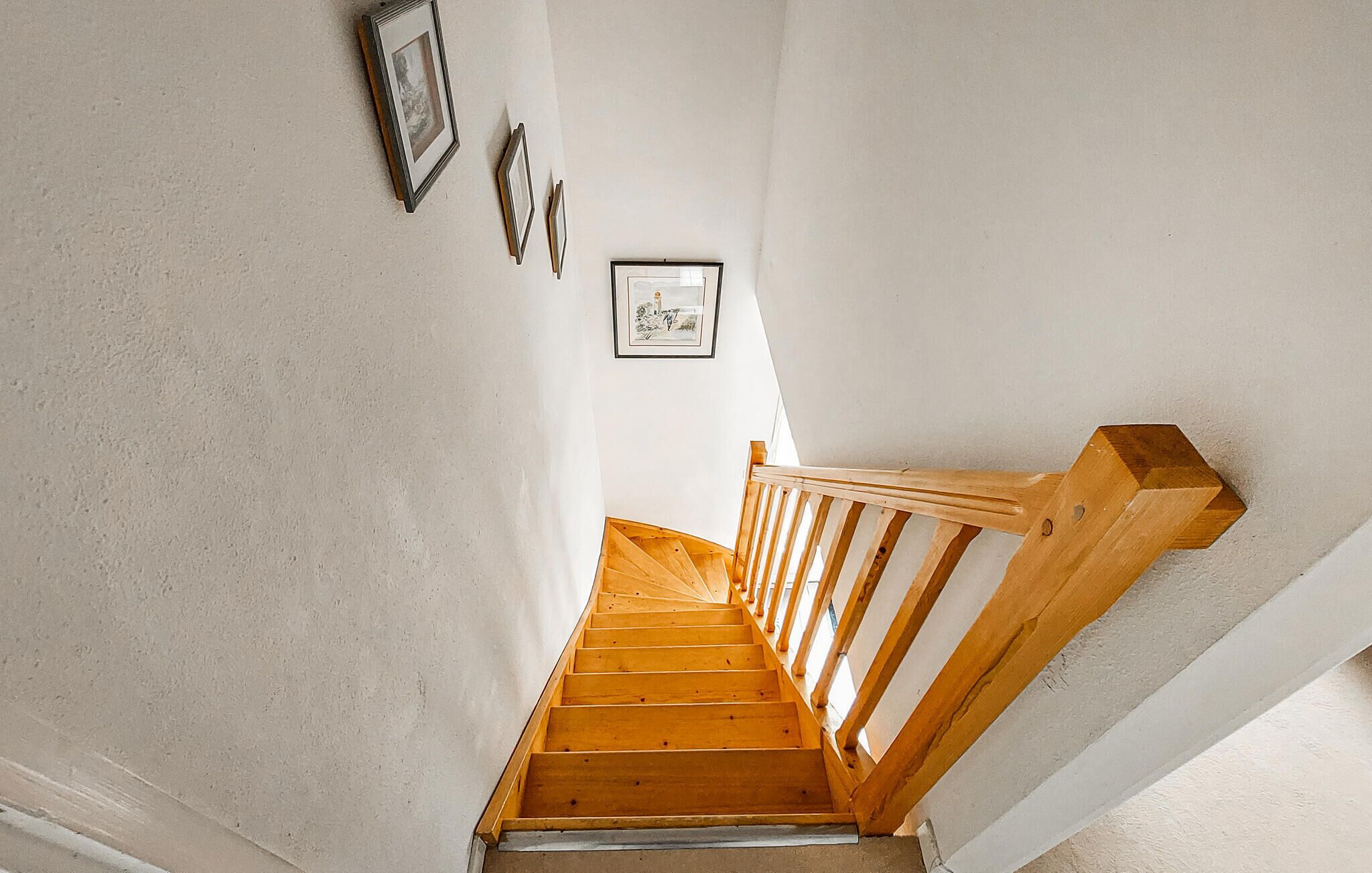 Un escalier en bois, doté d’une rampe, mène à un palier.