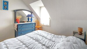 A bedroom with a bed, a dresser, a chair, a mirror, and a window.