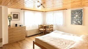 A bedroom with a wooden ceiling, a bed, a dresser, a chair, a table, and a radiator. - Moritzhaus, (Grächen), 1258 by Interhome (Grächen)