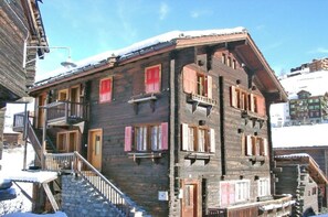 A multi-story wooden building with balconies and a staircase leading to the entrance. - Moritzhaus, (Grächen), 1258 by Interhome (Grächen)