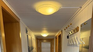 A narrow hallway with wooden flooring, a door with a metal handle, and a wall-mounted light fixture. - Moritzhaus, (Grächen), 1258 by Interhome (Grächen)