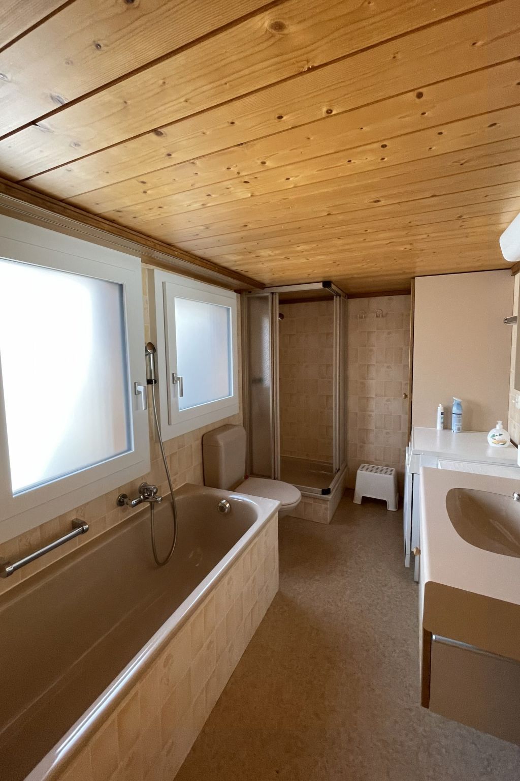 A bathroom with a wooden ceiling, a bathtub, a shower, and a sink.