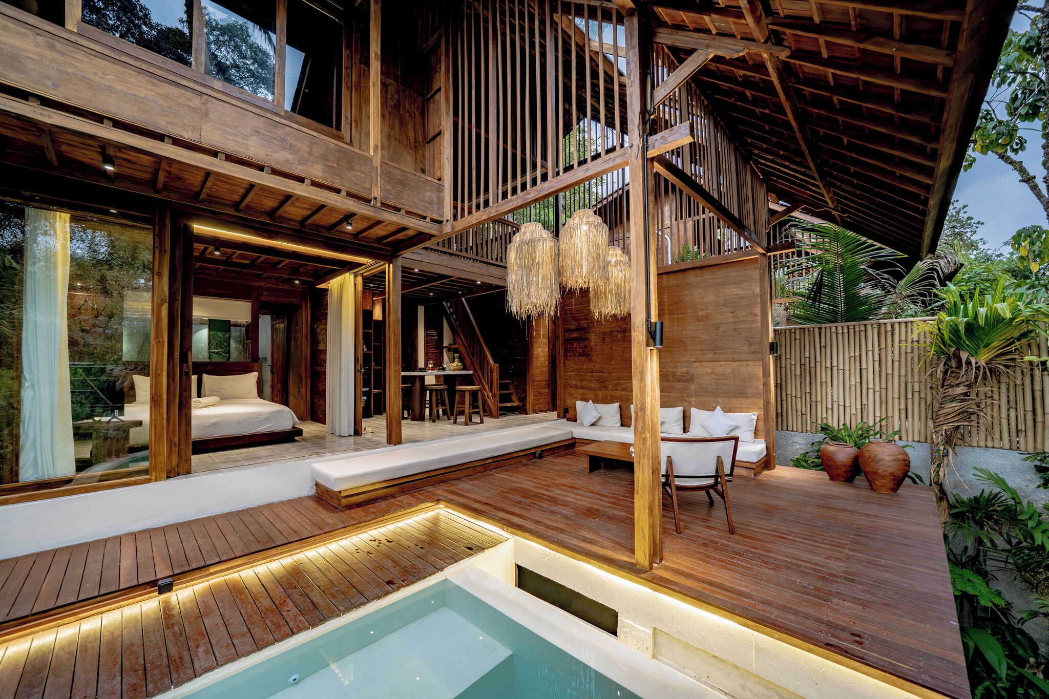 Un espacio exterior moderno con piscina, terraza de madera y zona de estar.