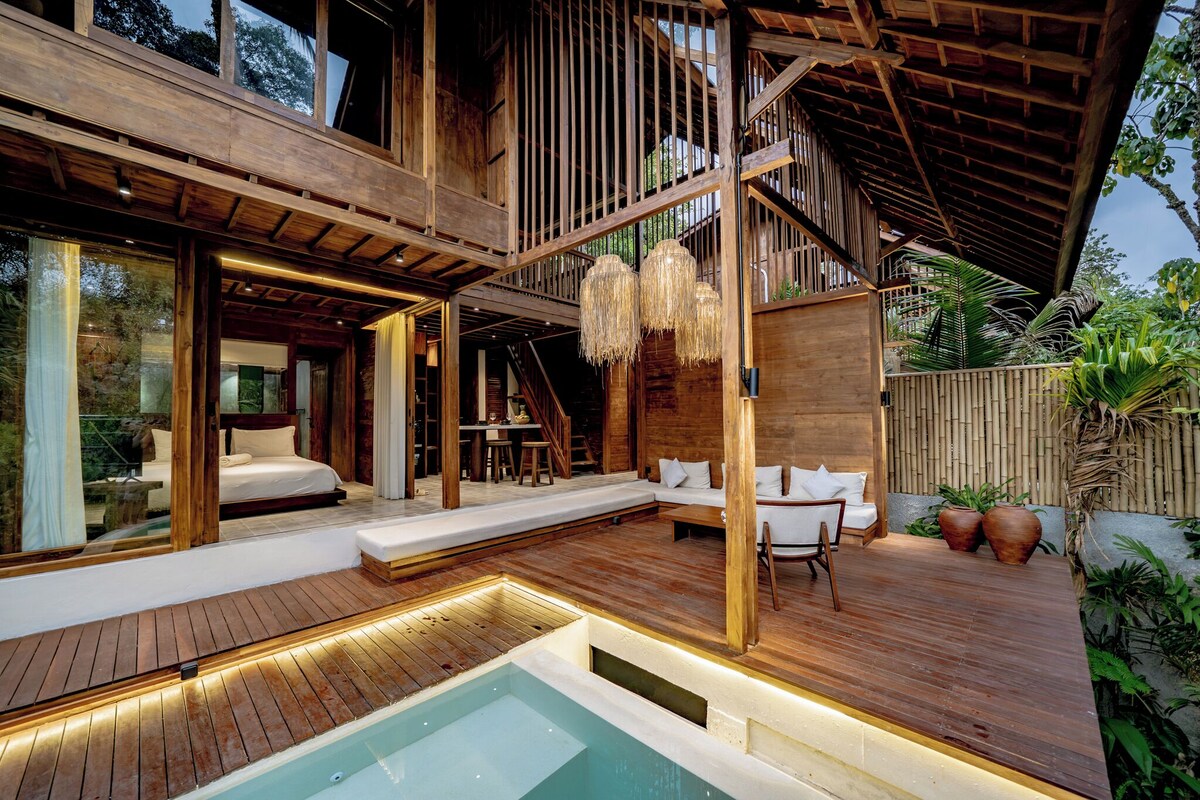 Un espacio exterior moderno con piscina, terraza de madera y zona de estar.