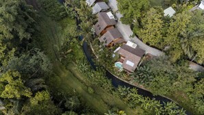 An aerial view of a residential area with houses surrounded by dense vegetation and a river. - Haven by The River Ubud (Ubud)