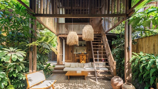 A wooden deck with a sofa, a coffee table, and a chair. There is a staircase leading to an upper level. - Haven by The River Ubud (Ubud)
