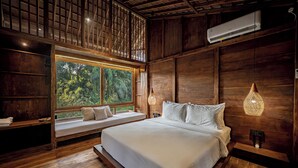 A bedroom with a large bed, a window seat, and a view of the outdoors. - Haven by The River Ubud (Ubud)