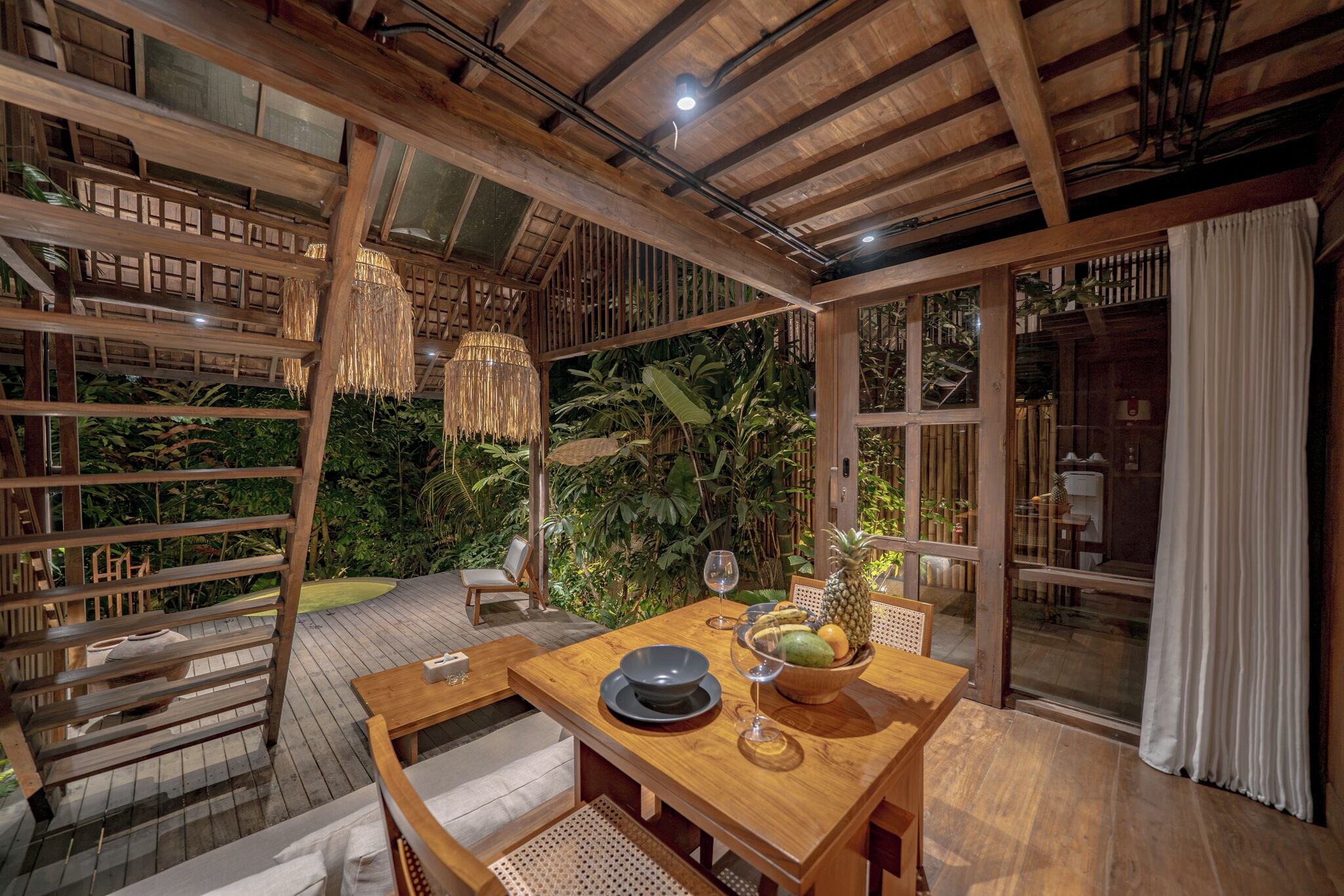 A wooden deck with a dining table, chairs, and a glass-top table.
