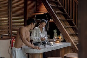 A kitchen with a wooden staircase, a fire extinguisher, and a fruit bowl on the counter. - Haven by The River Ubud (Ubud)