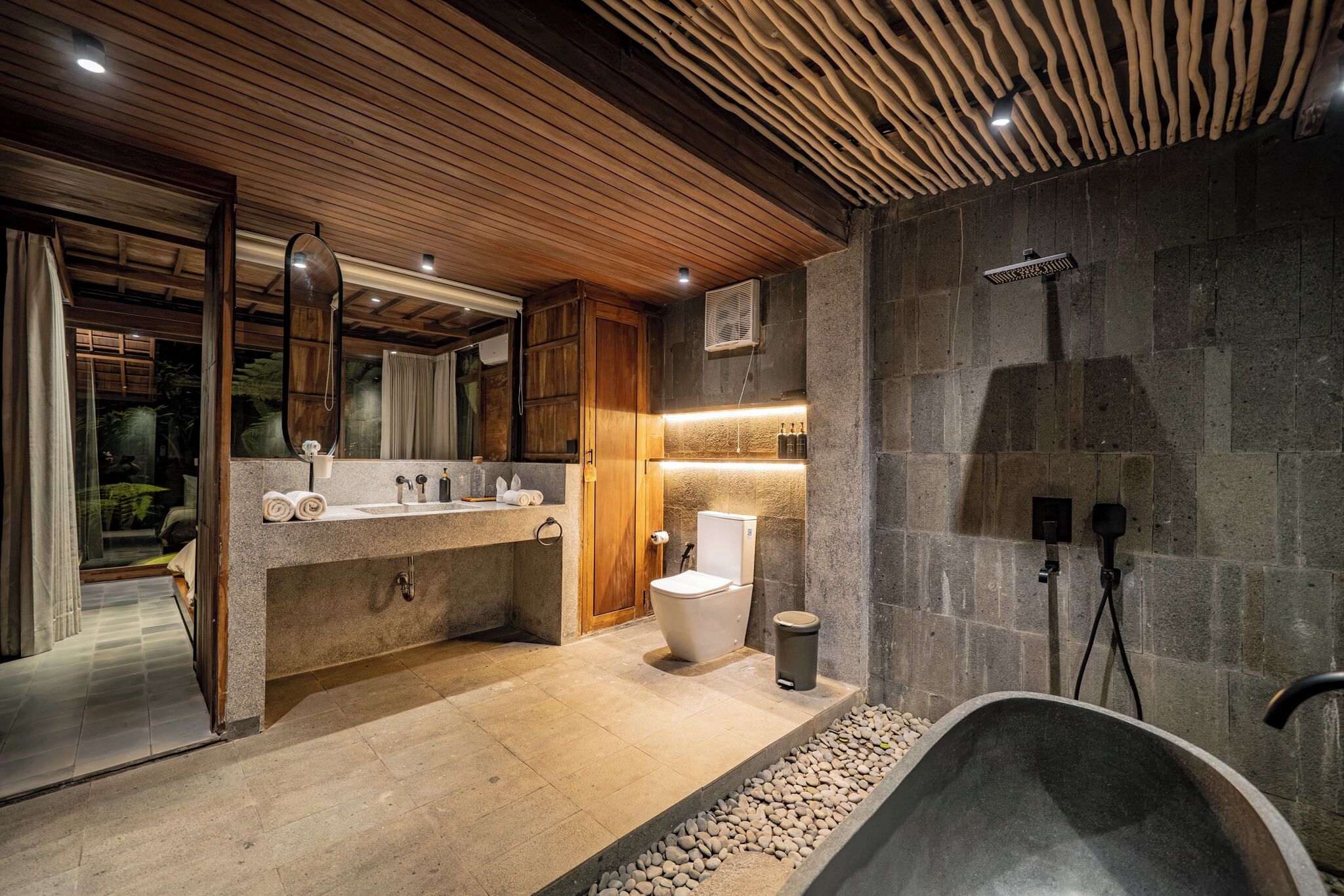 Un baño moderno con una bañera independiente, un espejo grande y un techo de madera.