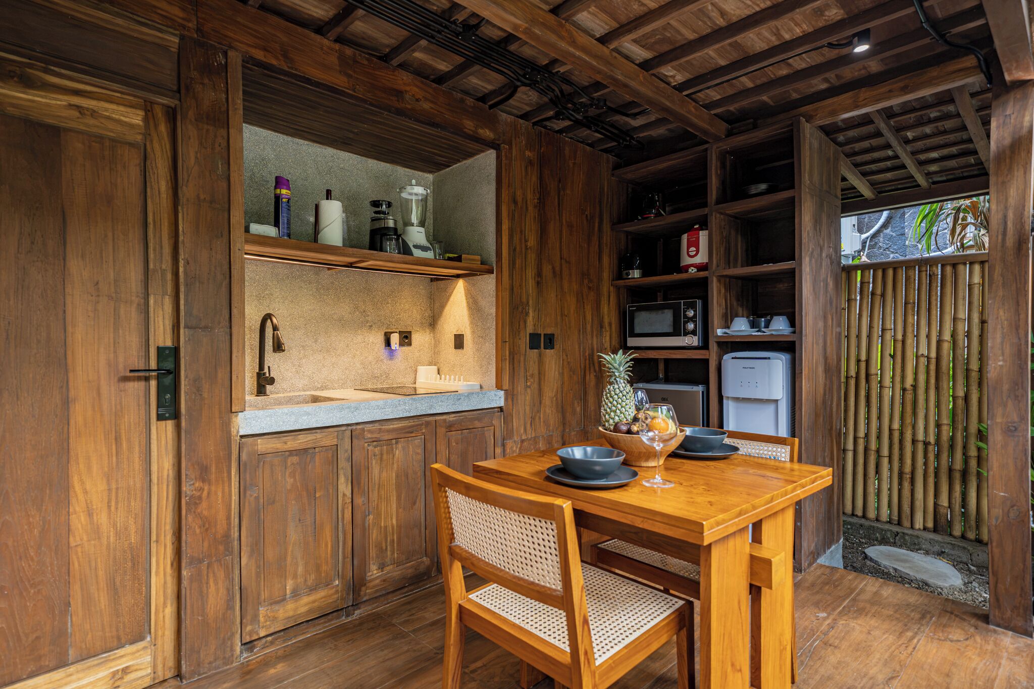 Una cocina de madera con pileta integrada, una mesa de comedor con sillas y un refrigerador.
