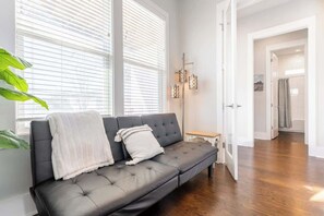 A modern living room with a dark leather sofa, a white throw blanket, and a small wooden side table. - 4BR East Nashville - Walk to Bars & Restaurants (Nashville)