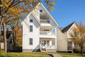 A two-story residential building with a front porch, a balcony on the upper floor, and a stone foundation. - 4BR East Nashville - Walk to Bars & Restaurants (Nashville)