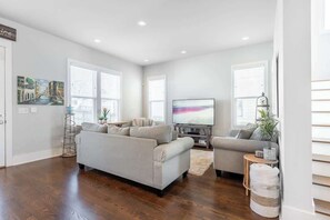 A modern living room with a grey sofa, a television, and a small side table. - 4BR East Nashville - Walk to Bars & Restaurants (Nashville)