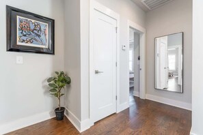 A hallway with a potted plant, a framed artwork, a white door, and a mirror on the wall. - 4BR East Nashville - Walk to Bars & Restaurants (Nashville)