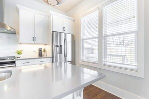 A modern kitchen with white cabinetry, a stainless steel refrigerator, and a large island. - 4BR East Nashville - Walk to Bars & Restaurants (Nashville)
