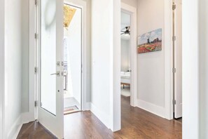 A hallway with white walls and wooden flooring, leading to a bedroom with a bed and a painting. - 4BR East Nashville - Walk to Bars & Restaurants (Nashville)