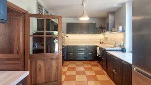 A kitchen with wooden cabinets, a tiled floor, and a hanging light fixture. - Domaine de luxe avec piscine (Meursac)