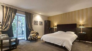 A hotel room with a large bed, a chair, a desk, and a view of the outdoors. - Domaine de luxe avec piscine (Meursac)