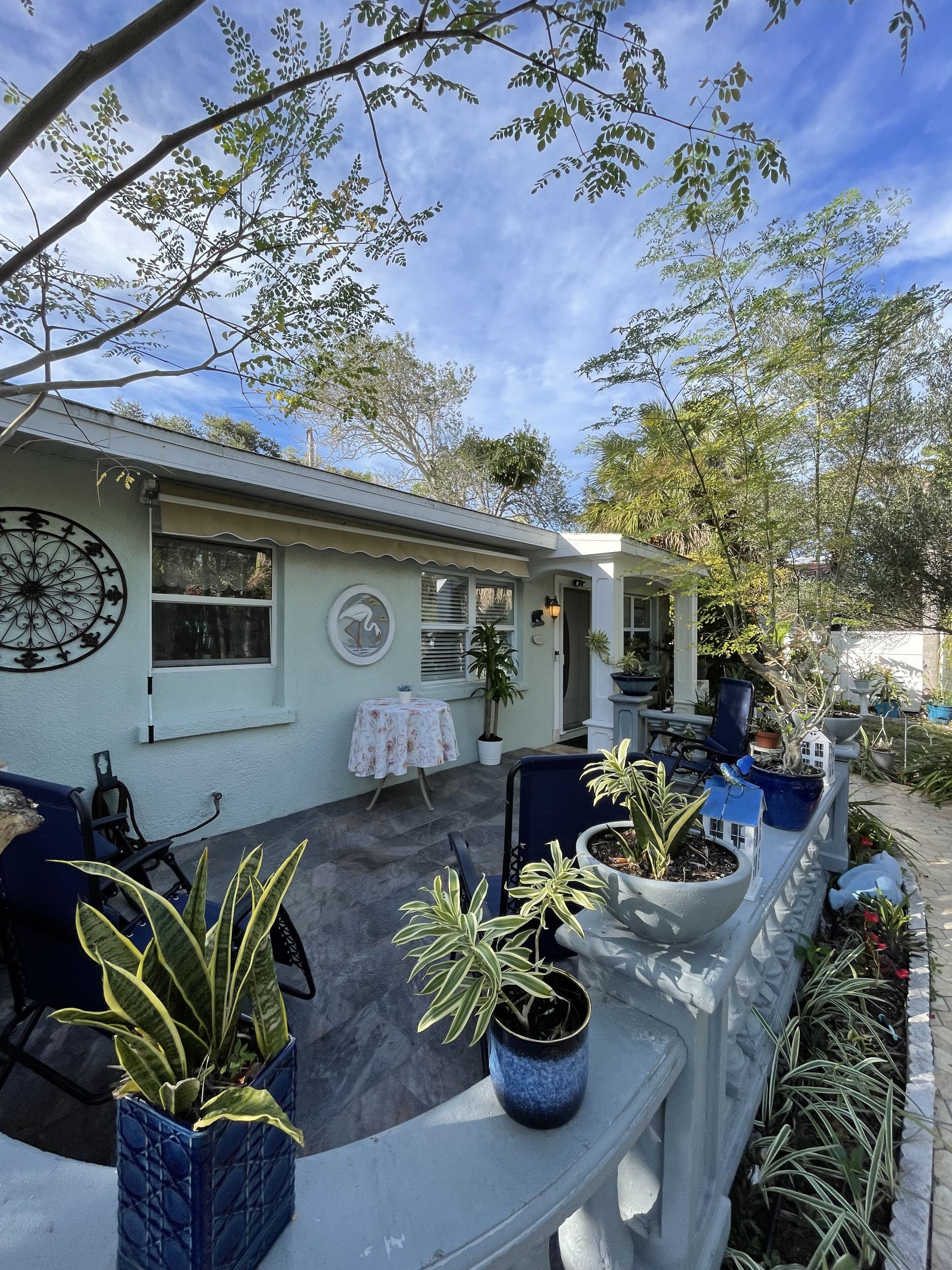 A house with a patio area featuring outdoor furniture and potted plants.