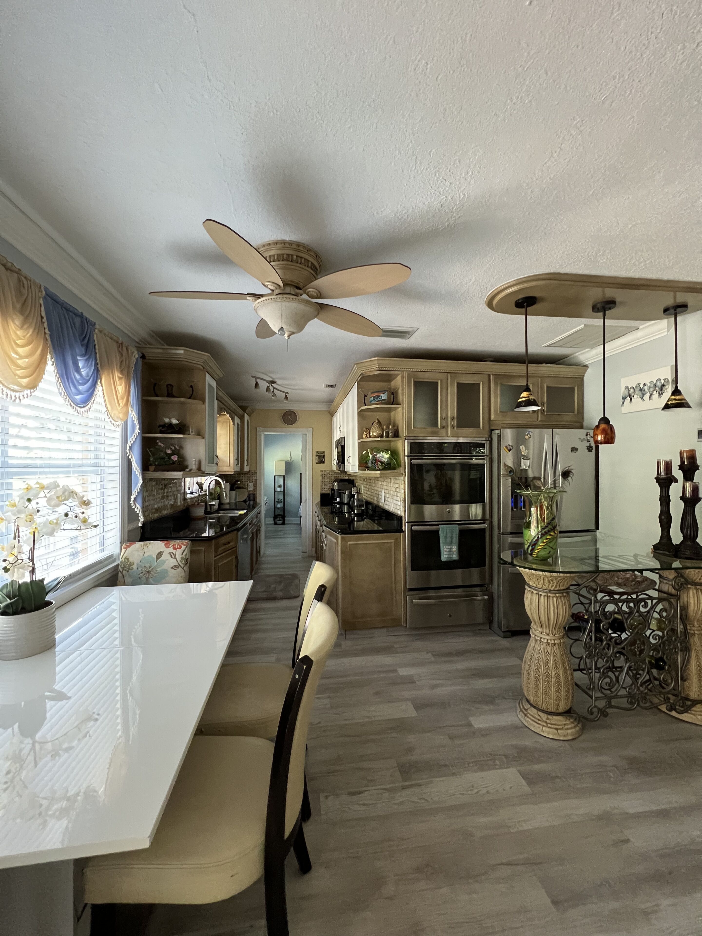 Una cocina moderna con una isla central, electrodomésticos de acero inoxidable y un ventilador de techo.