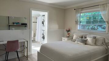 A bedroom with a bed, a desk, and a window with curtains.