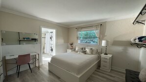 A bedroom with a bed, a desk, a chair, a window, and a nightstand.