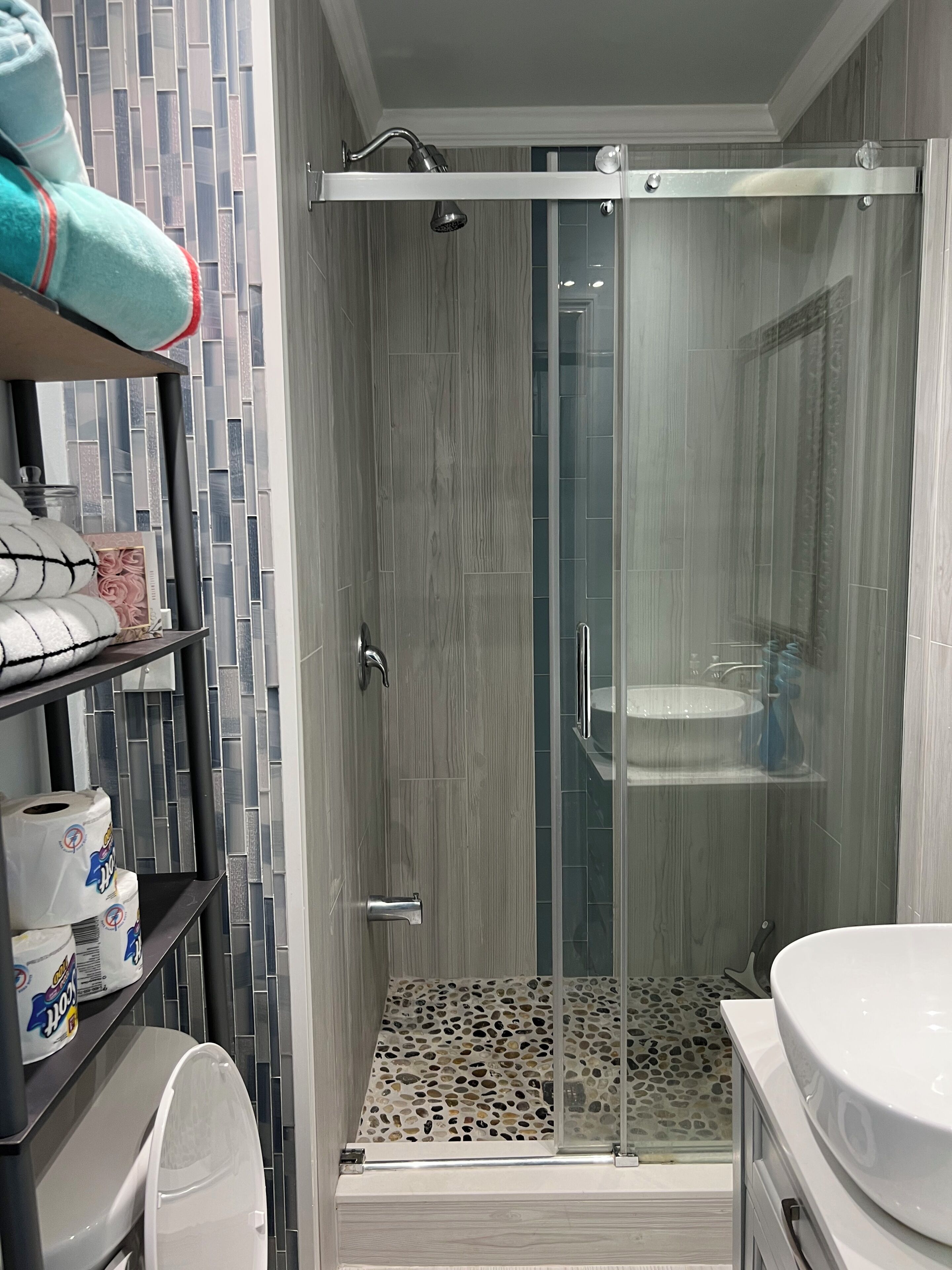 A modern bathroom with a glass-enclosed shower, a toilet, and a sink.