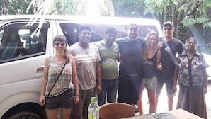 A group of people standing in front of a white van with a table and chairs nearby. - Ella Taxi (Ella)