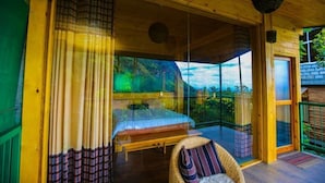 A room with a bed, a chair, and a view through a glass door. - Ella Taxi (Ella)