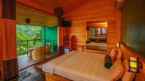 A wooden cabin bedroom with a bed, pillows, a nightstand, a mirror, and a view of the outdoors. - Ella Taxi (Ella)