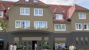A multi-story building with a sign reading 'The Great North.' There are multiple windows, a covered entrance, and a landscaped area with potted plants. - Thegreatnorth - Holstentherme Resort Hotel (Kaltenkirchen)