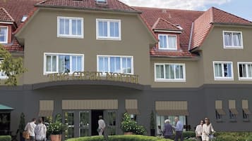 Ein mehrstöckiges Gebäude mit einem Schild, auf dem 'The Great North' steht. Es gibt mehrere Fenster, einen überdachten Eingangsbereich und eine bepflanzte Grünfläche mit Kübelpflanzen.