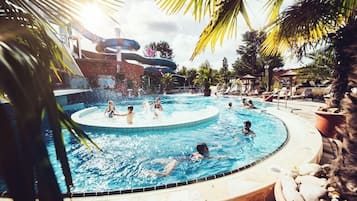 Ein Poolbereich mit mehreren Wasserrutschen und einer runden Whirlwanne, umgeben von Liegestühlen.