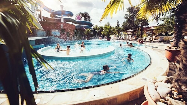 A pool area with multiple water slides and a circular hot tub surrounded by lounge chairs. - Thegreatnorth - Holstentherme Resort Hotel (Kaltenkirchen)
